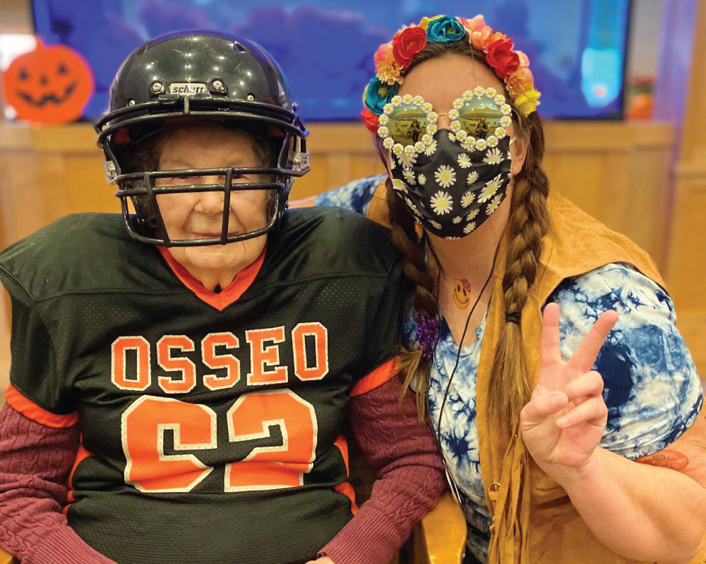 Senior woman wearing a football player costume younger woman next to her dressed like a flower child