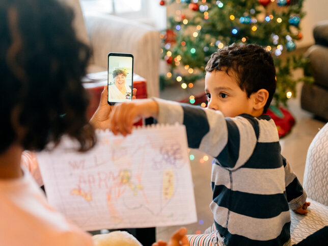GettyImages-1188715564 Little boy showing a picture he drew to his grandma over a virtual call.