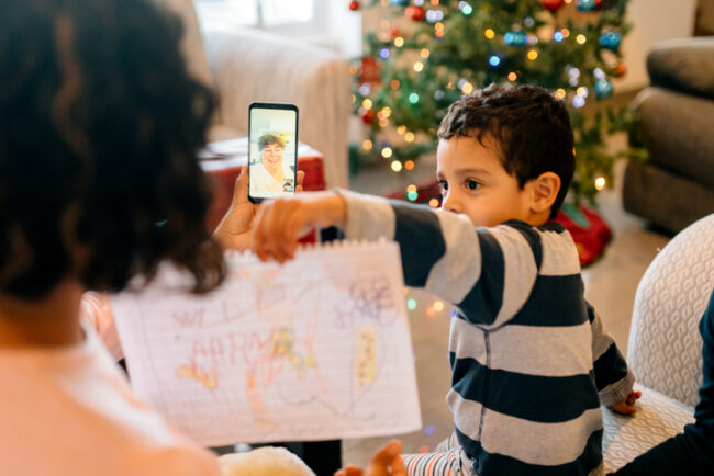 GettyImages-1188715564 Little boy showing a picture he drew to his grandma over a virtual call.