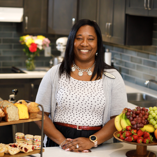 Staff member in the common kitchen where she has just put out pastries and fruit for snacks