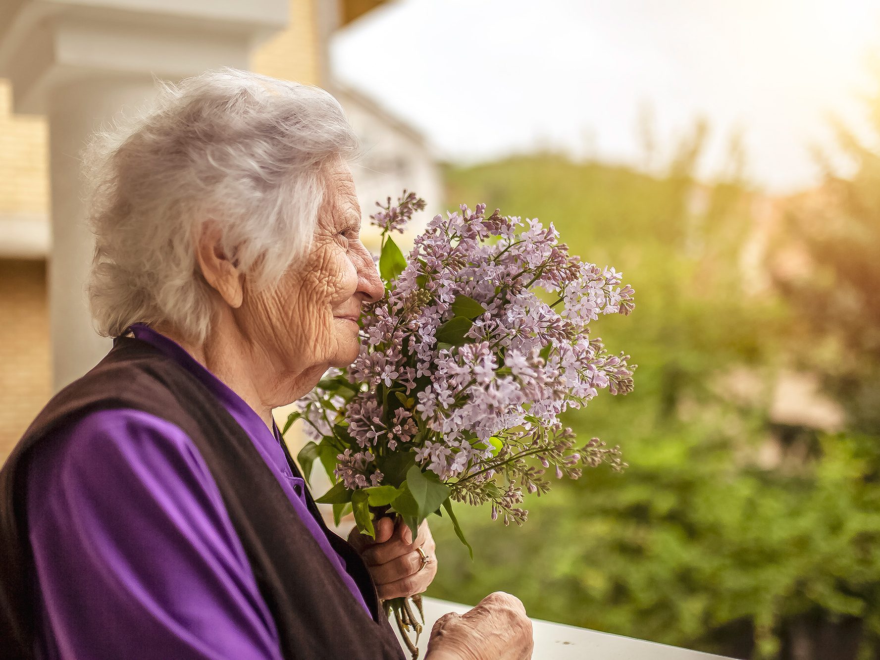 Senior woman smelling lilacs